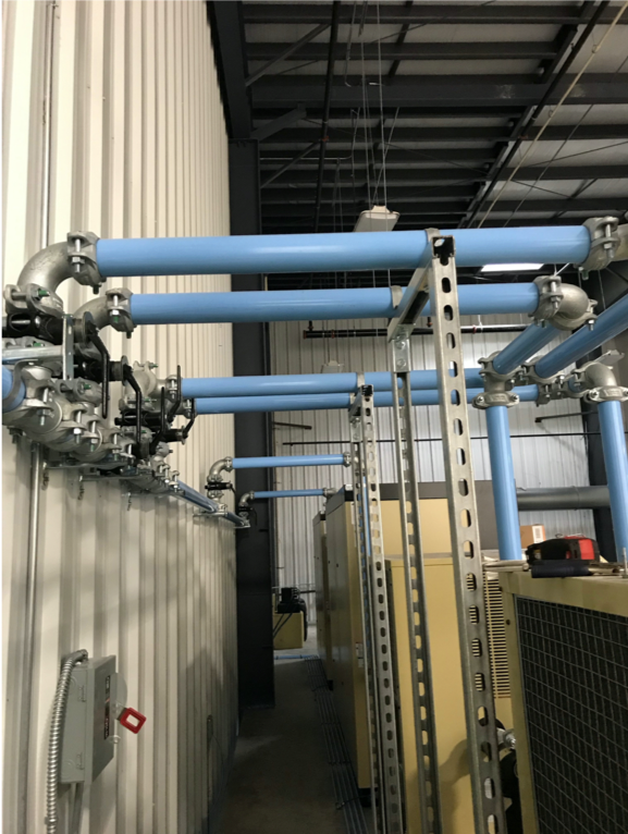 Industrial piping running along the ceiling of a facility, featuring valves and junctions for process control or distribution by Air Centers of Florida.